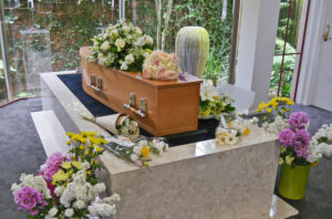 Funeral floral arrangements are surrounding and laying on top of a casket