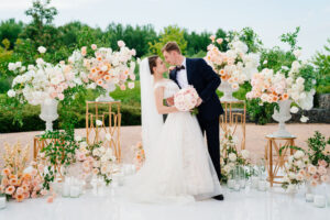 Beautiful bride and groom in the wedding ceremony area of live white and pink flowers.