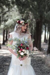 Woman holding bouquet of wedding flowers with flower crown on her head.
