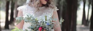Woman holding bouquet of wedding flowers with flower crown on her head.