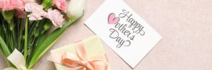 bouquet of different beautiful flowers with greeting card and gift box on beige background. mother's day celebration